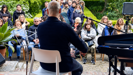 Público frente a un músico durante un concierto en el jardín del Museo Larreta